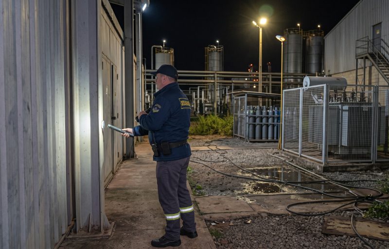 Vigilante fazendo a ronda noturna com lanterna ao lado do tanque